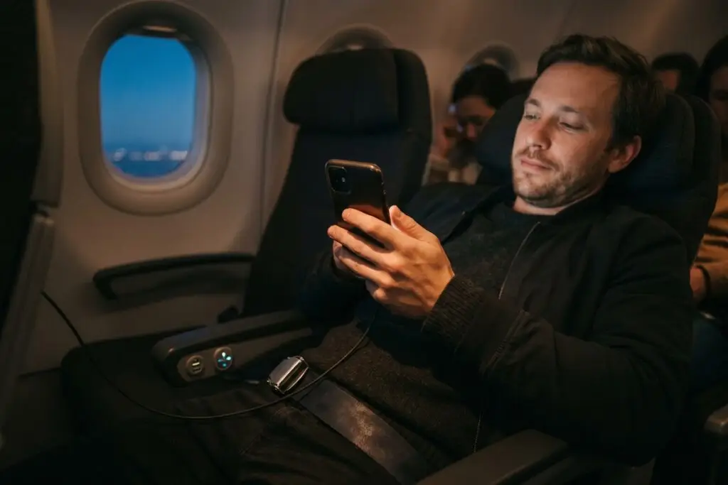Person adjusting phone settings to extend battery life on a long flight